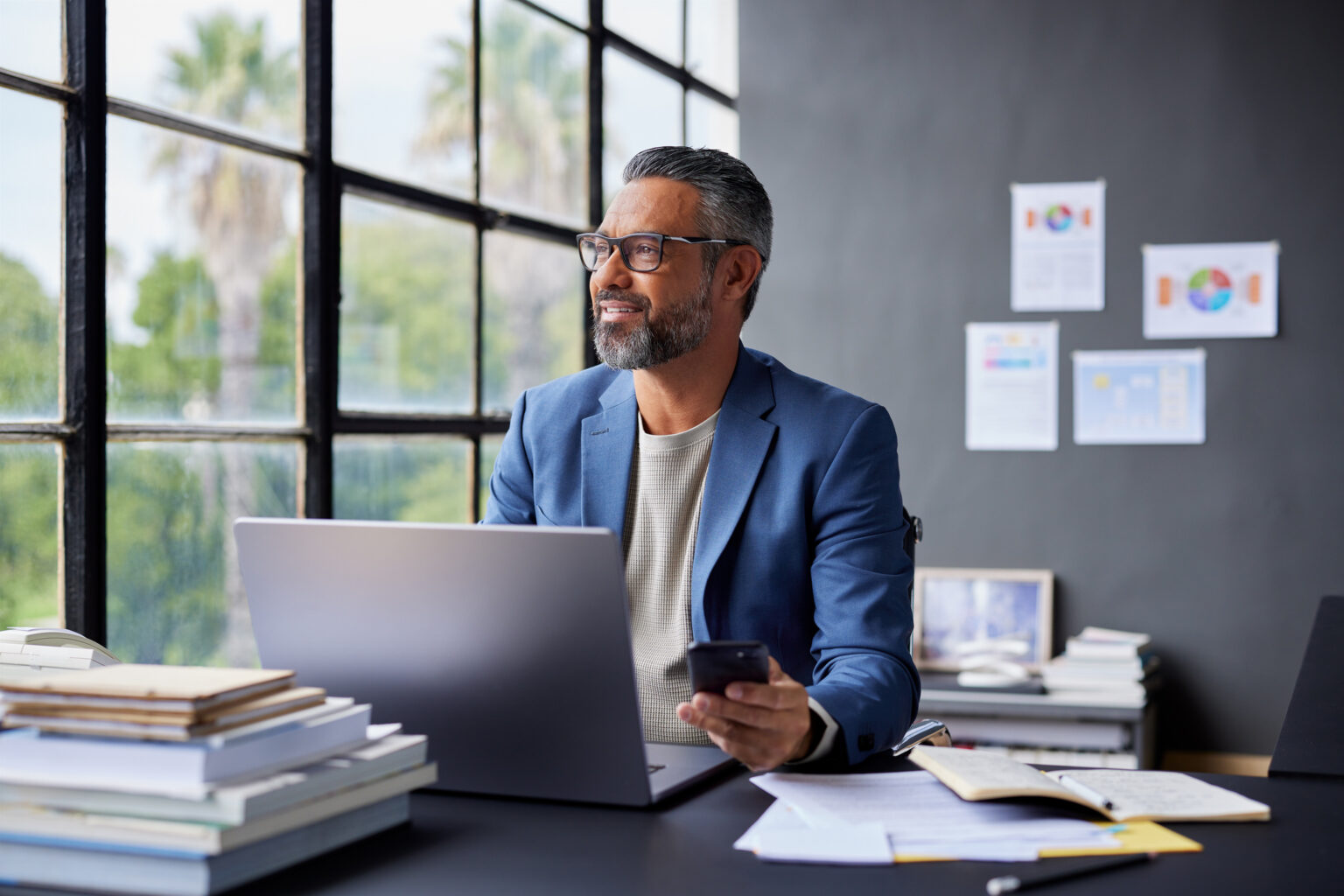 Financial advisor sitting at his office desk looking out the window, planning how to grow AUM, attract better clients, and build a scalable advisory firm with proven systems.